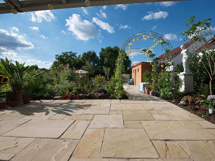 Natürlicher Garten mit hellem Sandstein Yellow Mint und strahlend blauem Himmel