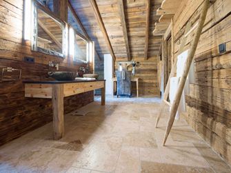Badezimmer mit Holzwänden und Natursteinboden in beige-braun