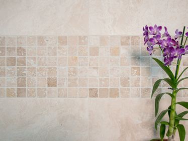 Une orchidée devant le mur en mosaïque en travertin clair