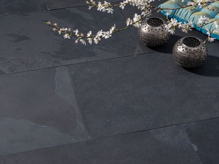Les dalles Mustang en ardoise noire, un coussin, des bougies et des fleurs