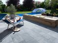 Femme se détend sur chaise longue sur terrasse en pierre calcaire Blaustein Azur avec vue sur piscine