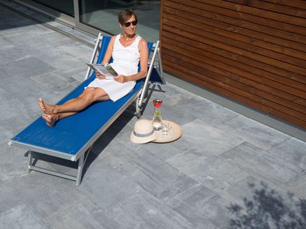 Une dame se détent sur sa terrasse en pierre bleue Azur