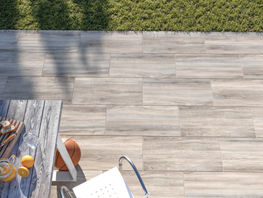 Vue sur la terrasse imitation bois avec les dalles Amber Oak et une table