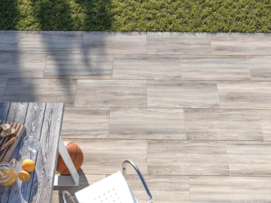 Vue sur la terrasse imitation bois avec les dalles Amber Oak et une table
