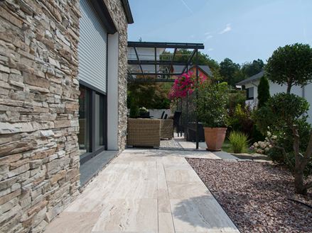 Une terrasse en travertin Natura et des plaquettes de parement au mur