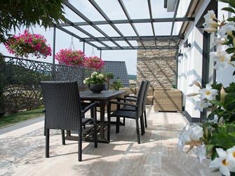 Terrasse moderne avec dalles de travertin Natura en aspect bois et meubles en osier foncé