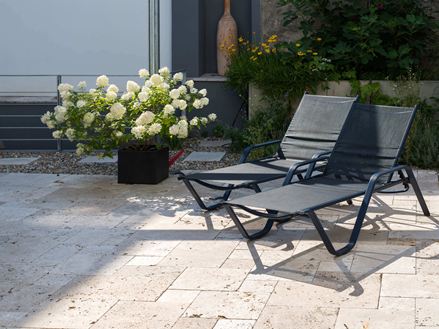 Deux chaises longues et pot de fleurs sur dalles en travertin Rustic