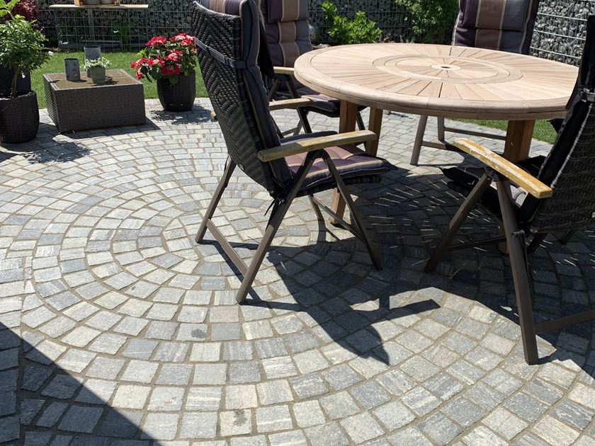 Les pavés en gneiss Urban Grey Line sur une terrasse avec table de jardin