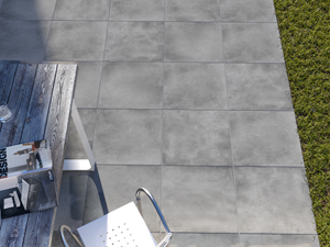 Vue sur une terrasse habillée de dalles effet béton Ombra, aperçu du gazon et du mobilier extérieur