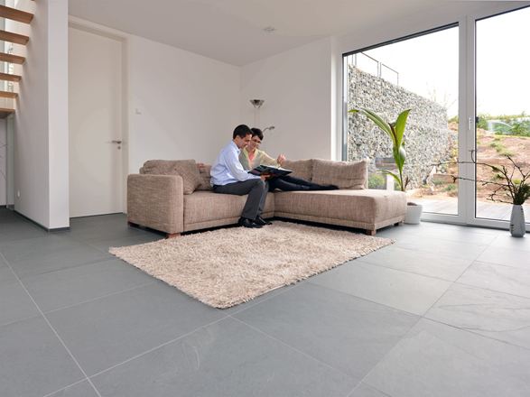 Ardoise grand format Grey Slate dans le salon avec canapé et murs blancs. Un couple est assis sur le canapé