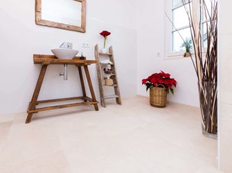 Salle de bains avec meubles en bois et carrelage en pierre naturelle claire en pierre calcaire comme revêtement de sol
