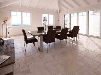 Salle à manger avec haut plafond, table et chaises sur travertin Light en assemblage romain