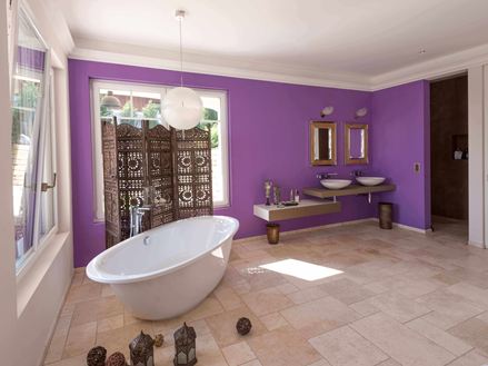 Salle de bains avec carrelage en travertin Light, mur violet et baignoire sur pied