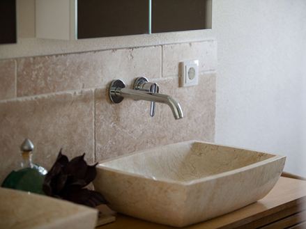Les carreaux de travertin Medium ont été posés au mur derrière le lavabo