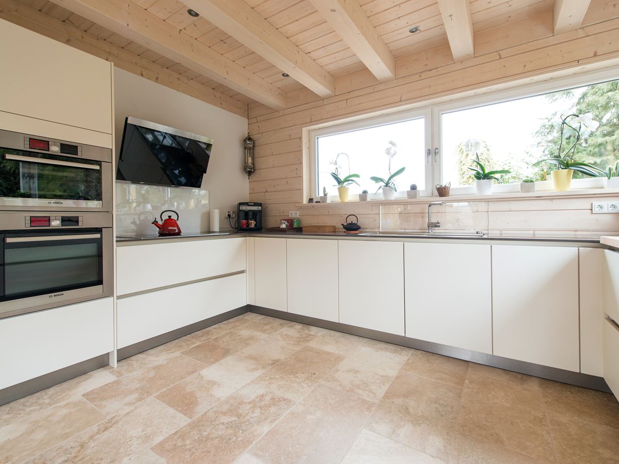 Des éléments de cuisine blancs et un sol en travertin Rustic