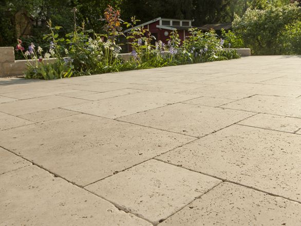 Dalle Medium SELECT, en travertin avec un massif de fleurs en arrière plan
