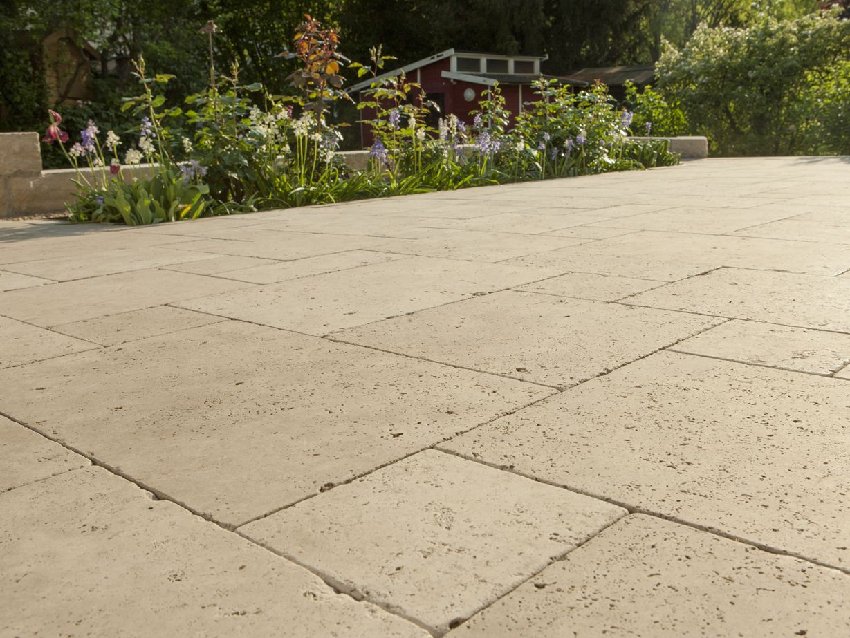 Dalle Medium SELECT, en travertin avec un massif de fleurs en arrière plan