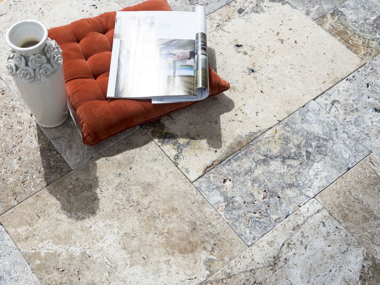 Un oreiller rouge, un vase et un magazine sur des dalles de travertin Silver