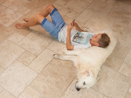 Un garçon se couche avec son chien sur le sol en travertin