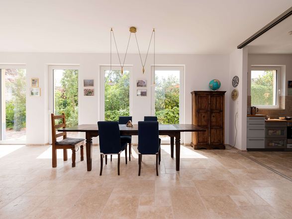 Heller Essbereich mit Holzmöbeln und Travertinfliesen in Beige als Bodenbelag