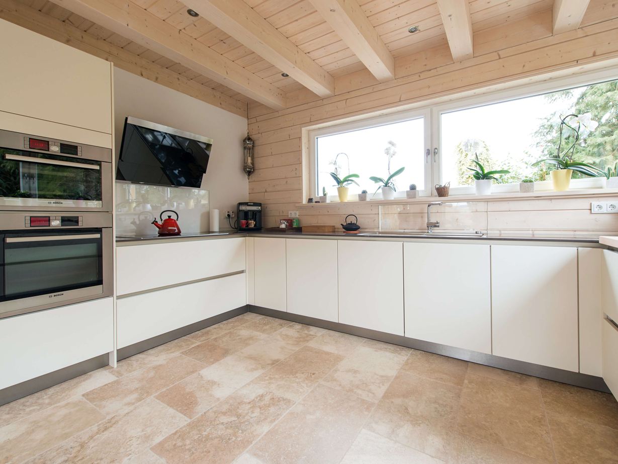 Des éléments de cuisine blancs et un sol en travertin Rustic
