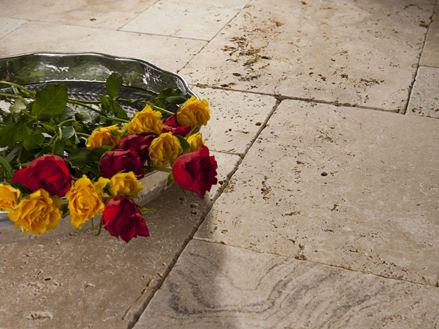Un plateau avec des roses sur des dalles en travertin posées en beige et brun