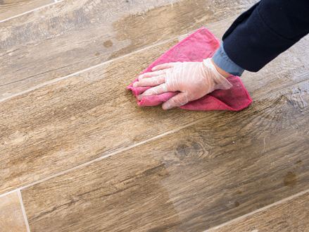 Une main s'essuie avec un chiffon sur un carreau de grès cérame