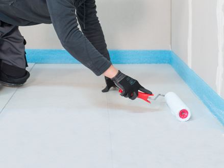 Le carreleur applique l'apprêt avec un rouleau